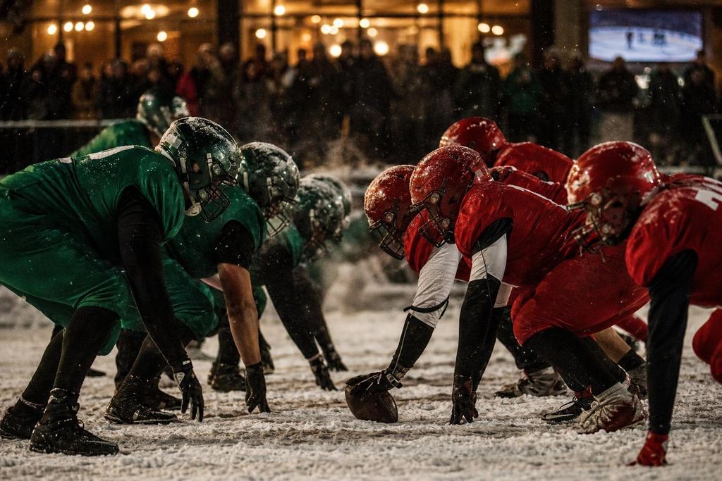 Canadian football players in red and green uniforms at the line of scrimmage in snow (AI-generated image)
