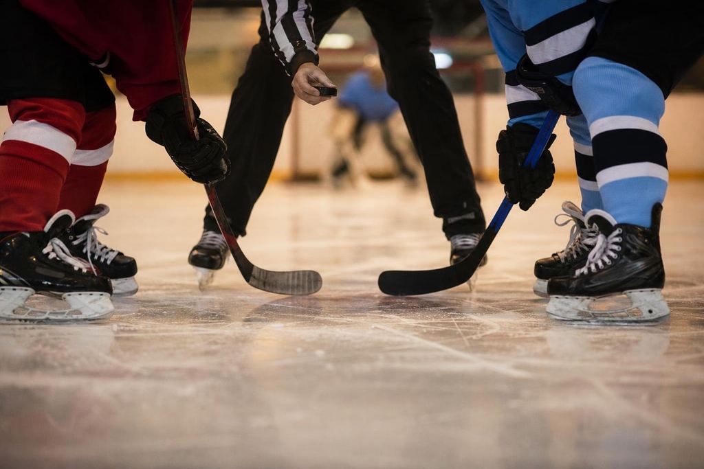 Two hockey players, one in red and one in blue, at a centre-ice faceoff (AI-generated image)