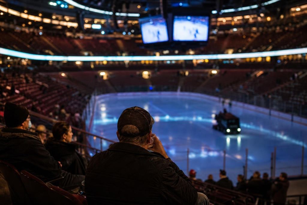 An empty arena bowl lit cool blue as a resurfacing machine leaves freshly cleaned ice (AI-generated image)