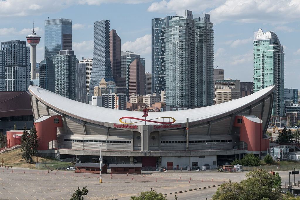 The Scotiabank Saddledome with the Calgary skyline rising behind it on a clear day